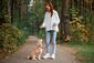 Eine junge Frau führt mit ihrem Hund das Kommando „Sitz“ aus.