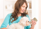 Eine Frau hält ihren Hund auf dem Arm und schaut sich eine Hundefutterdose an.
