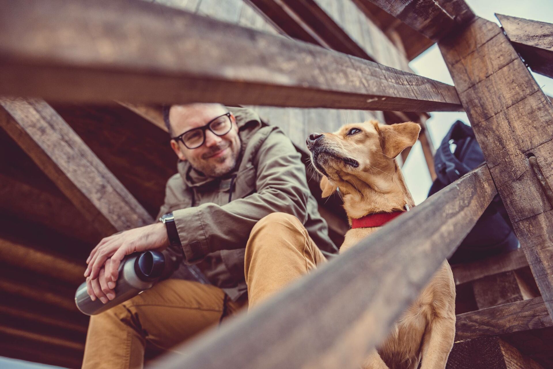 Hund und Halter sitzen auf Holztreppe.