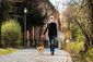 Ein Mann mit Atemschutzmaske geht mit seinem angeleinten Hund spazieren.