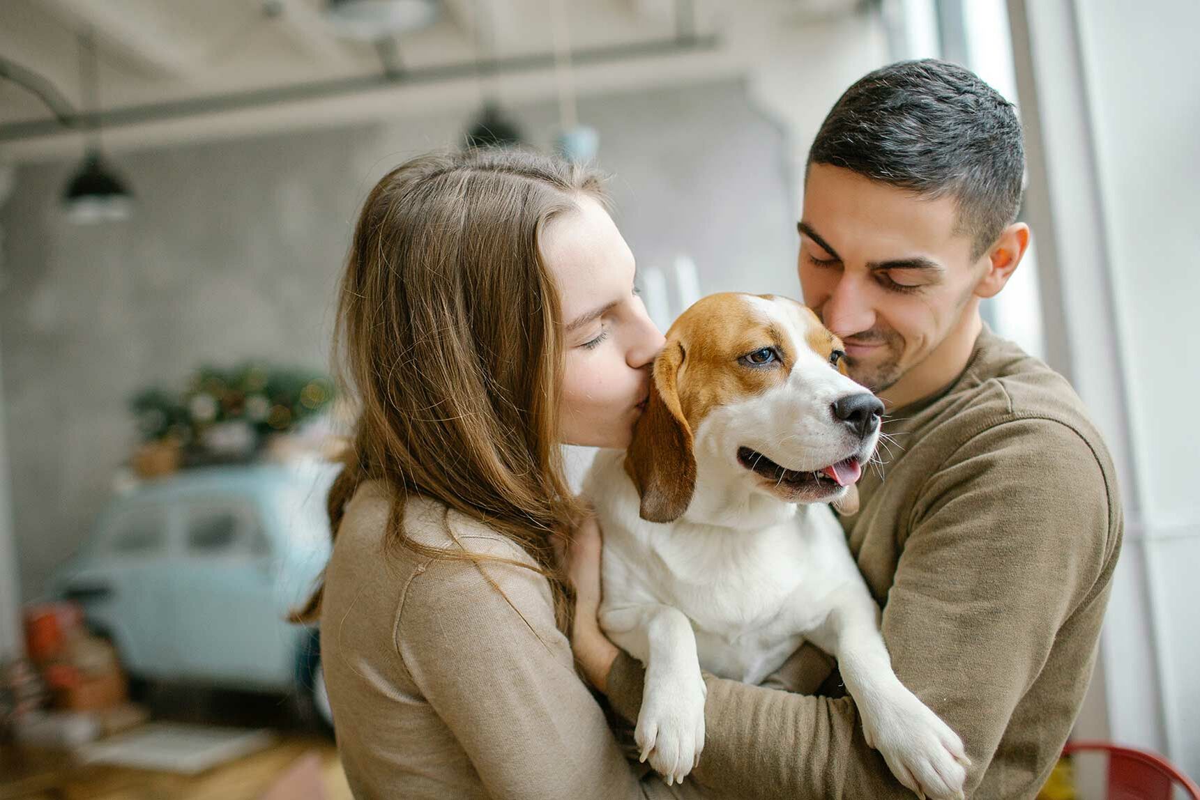 Ein Pärchen kuschelt mit einem Hund. 