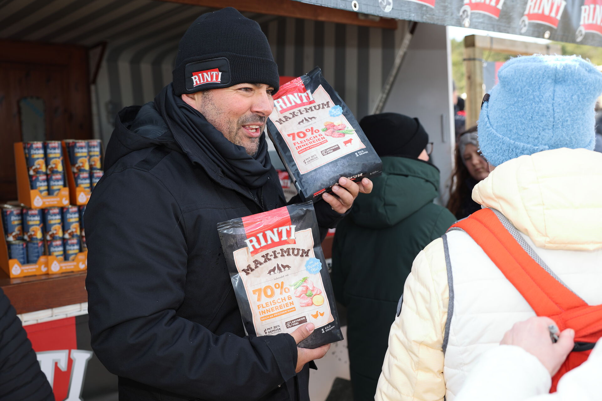 Antonio Krahl hält freundlich lachend zwei Rinti Futterpakete in die Luft.