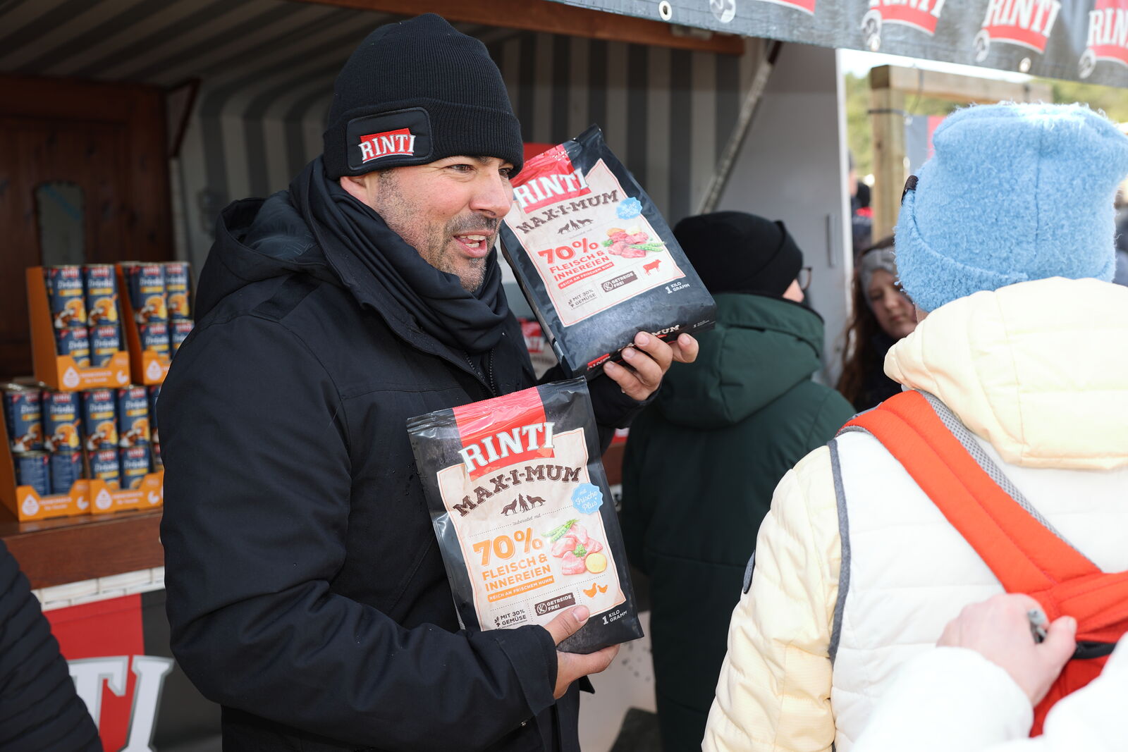 Antonio Krahl hält freundlich lachend zwei Rinti Futterpakete in die Luft.