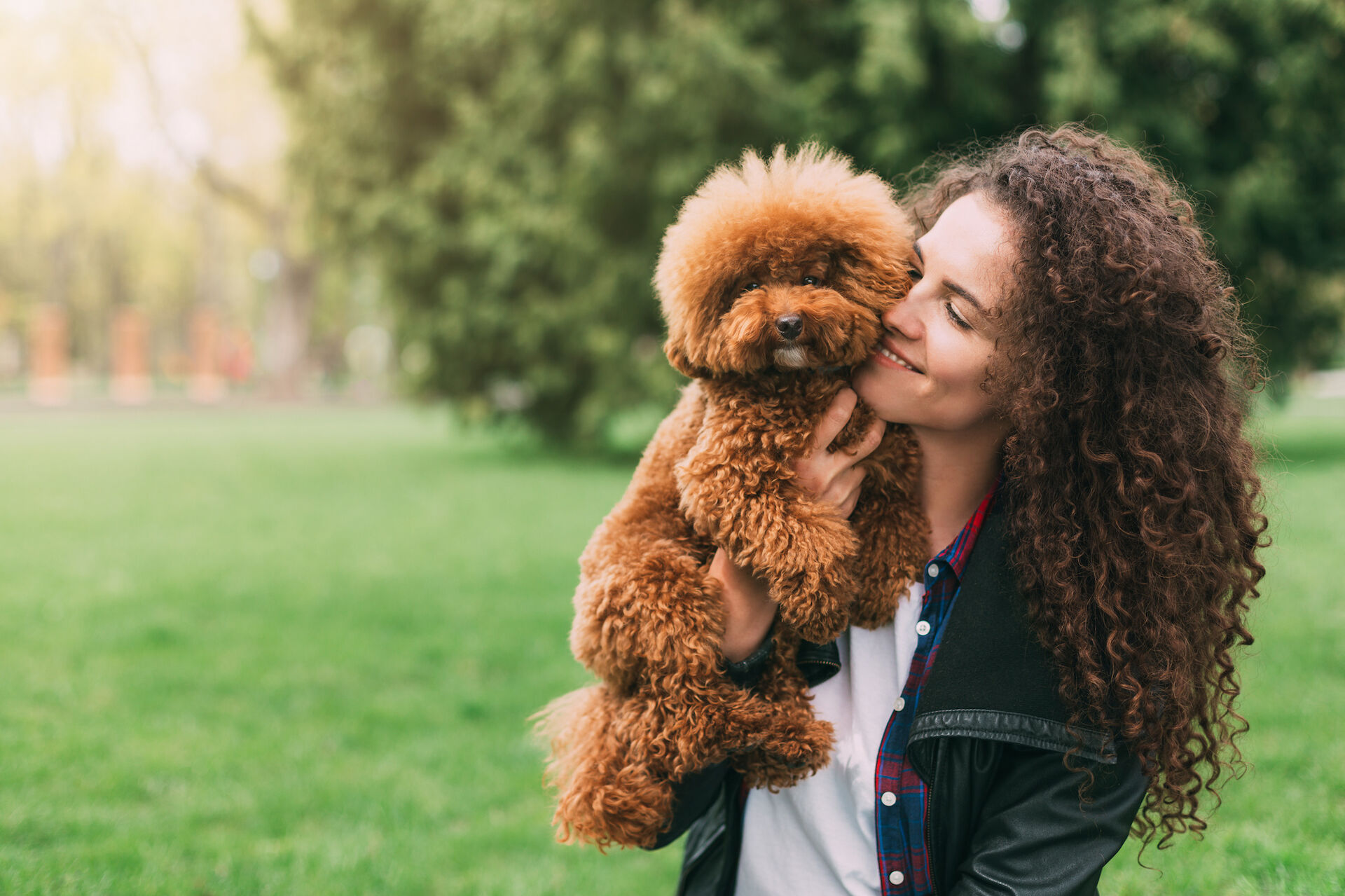 Eine fröhliche junge Frau umarmt einen Hund.