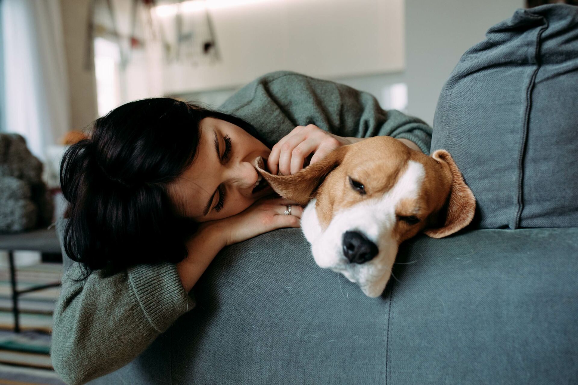 Ein Hund und eine Frau liegen nah beieinander auf einem Sofa.