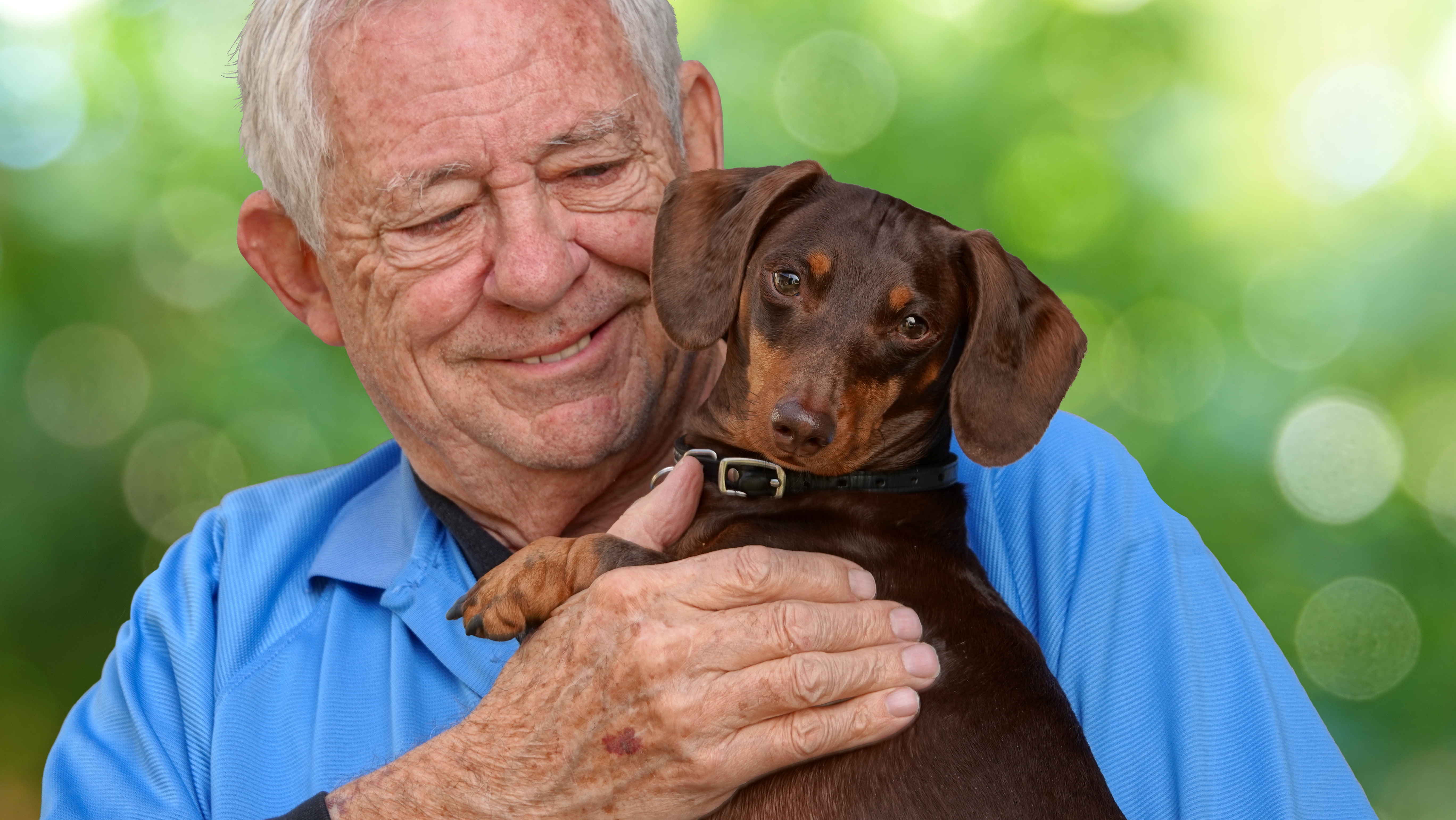 Ein alter Mann freut sich darüber, einen Dackel auf dem Arm zu halten.
